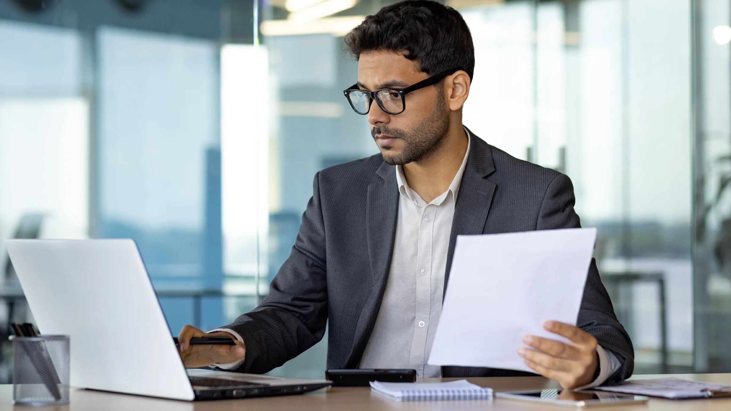 man holding papers and looking at a computer screen