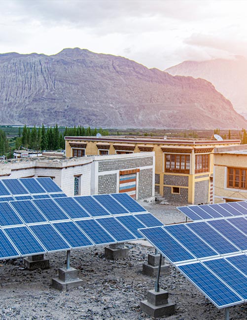 As the sun sets, solar panels collect power in a small rural Indian town near the mountains.