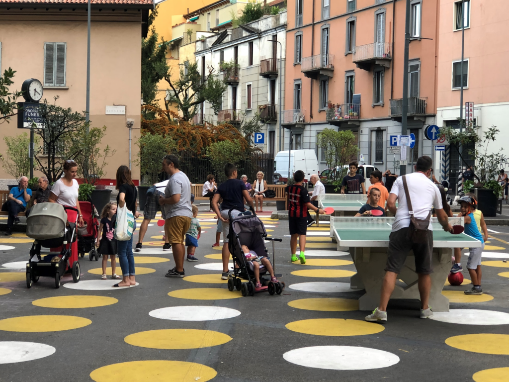 Ping-pong, picnic tables and planters create a neighborhood gathering place out of a parking lot in an outlying Milan neighborhood.
