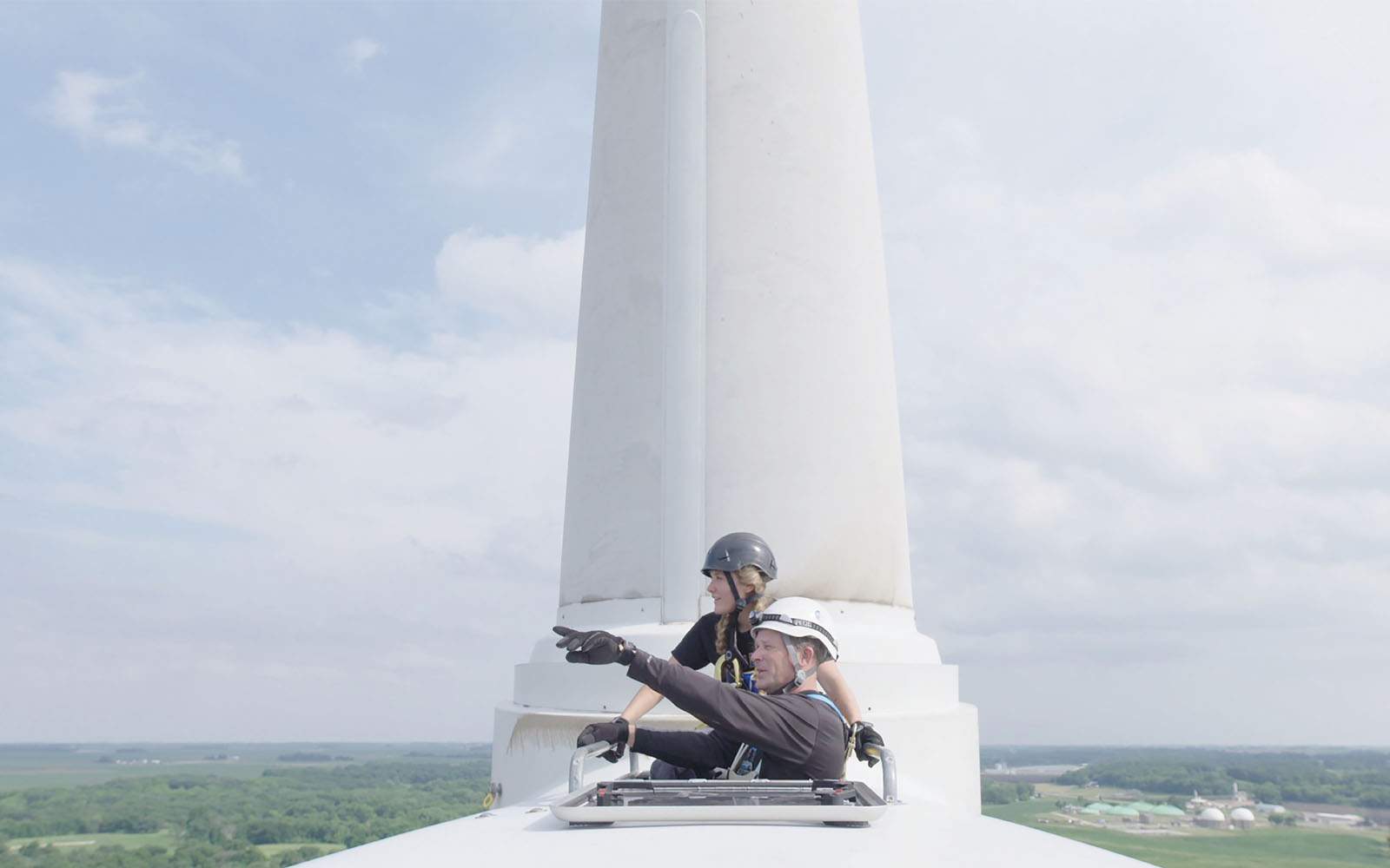 A community college student in Iowa studying wind energy, who is featured in Paris to Pittsburgh, looks out from the top of a turbine with her father.