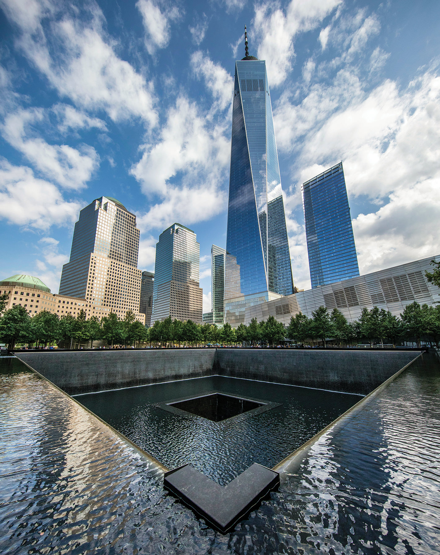 The One World Trade Center building rises above the reflecting pools at the 9/11 Memorial in Lower Manhattan.
