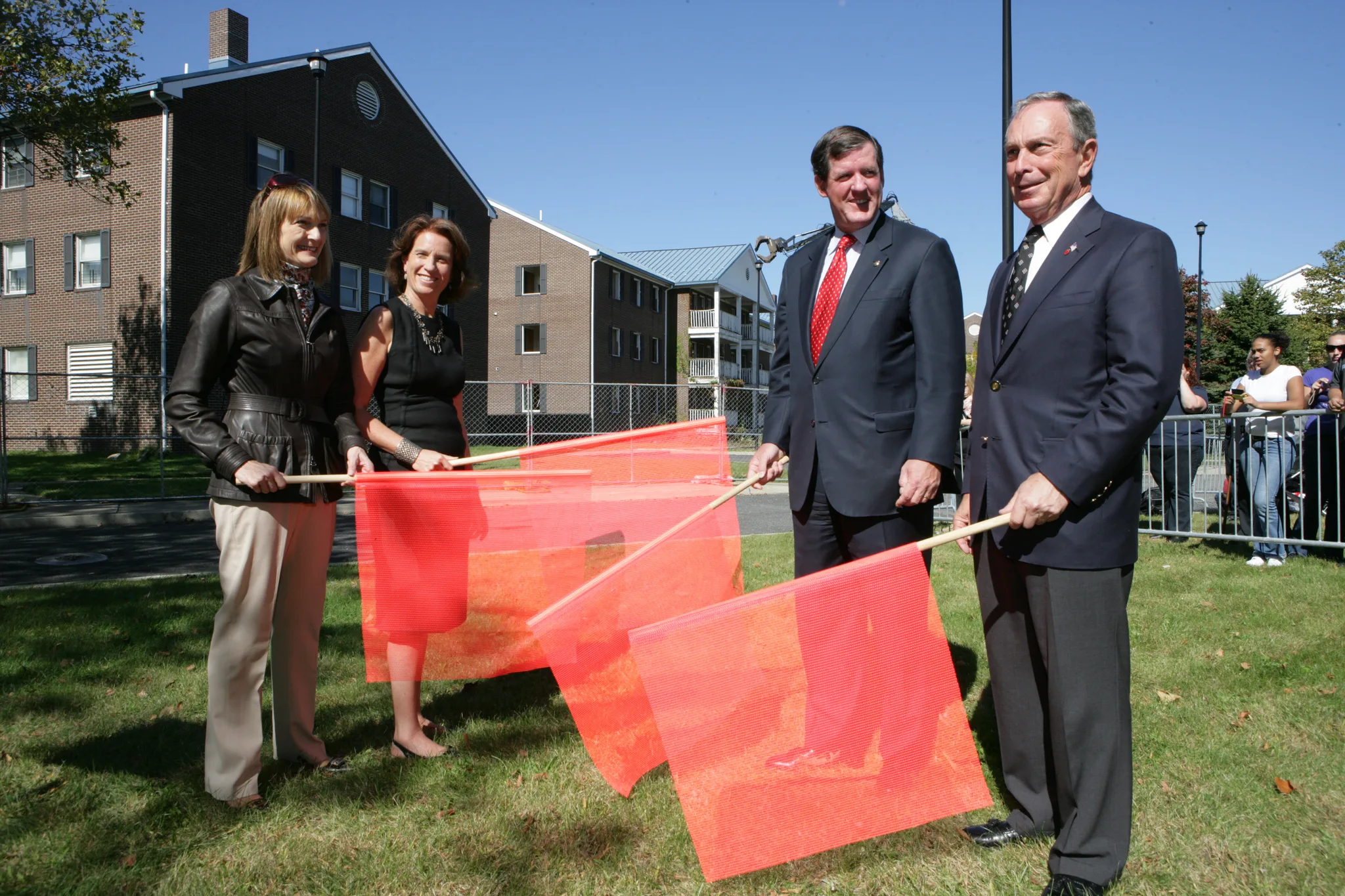 Patti Harris, Governors Island Preservation and Education Corporation President Leslie Koch, Deputy Mayor Robert Lieber, and Mike Bloomberg standing with red flags Patti Harris, Governors Island Preservation and Education Corporation President Leslie Koch, Deputy Mayor Robert Lieber, and Mike Bloomberg standing with red flags