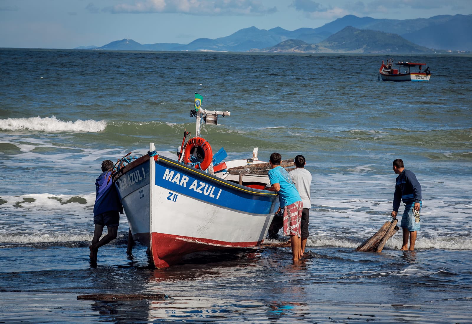 Fishermen in Fortaleza, Brazil stand on the shore by their boat. Photo credit: Bento Viana Photography