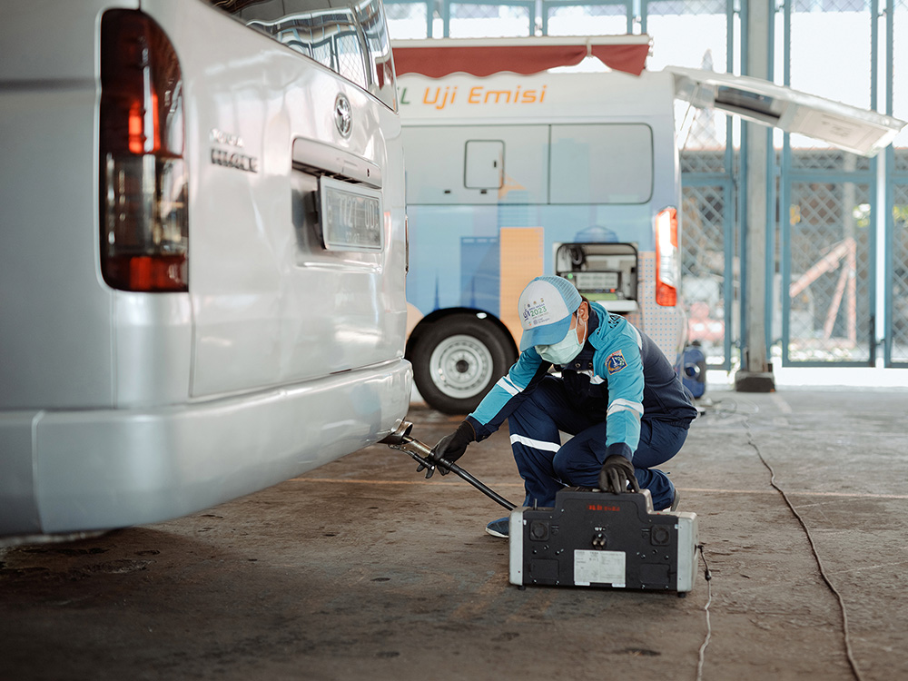 Technician in Jakarta tests vehicle emissions to support air pollution reduction initiatives.