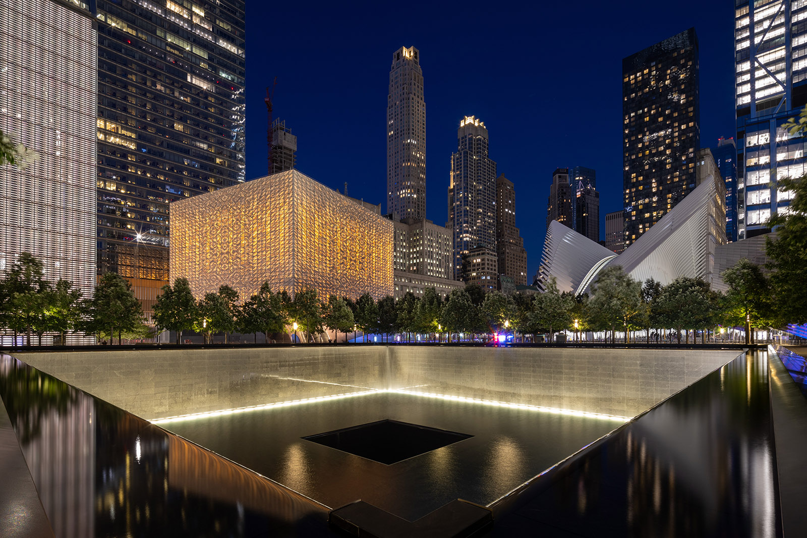 The Perelman Performing Arts Center illuminated at night next to the 9/11 Memorial in Lower Manhattan.