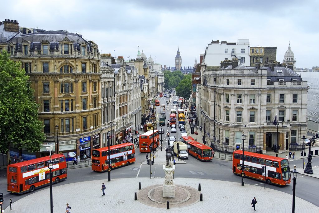Aerial view of central London featuring red double-decker buses and iconic city landmarks.