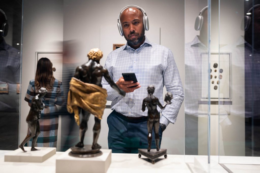 Middle-aged man listening to the Bloomberg Connects app narration for an exhibit