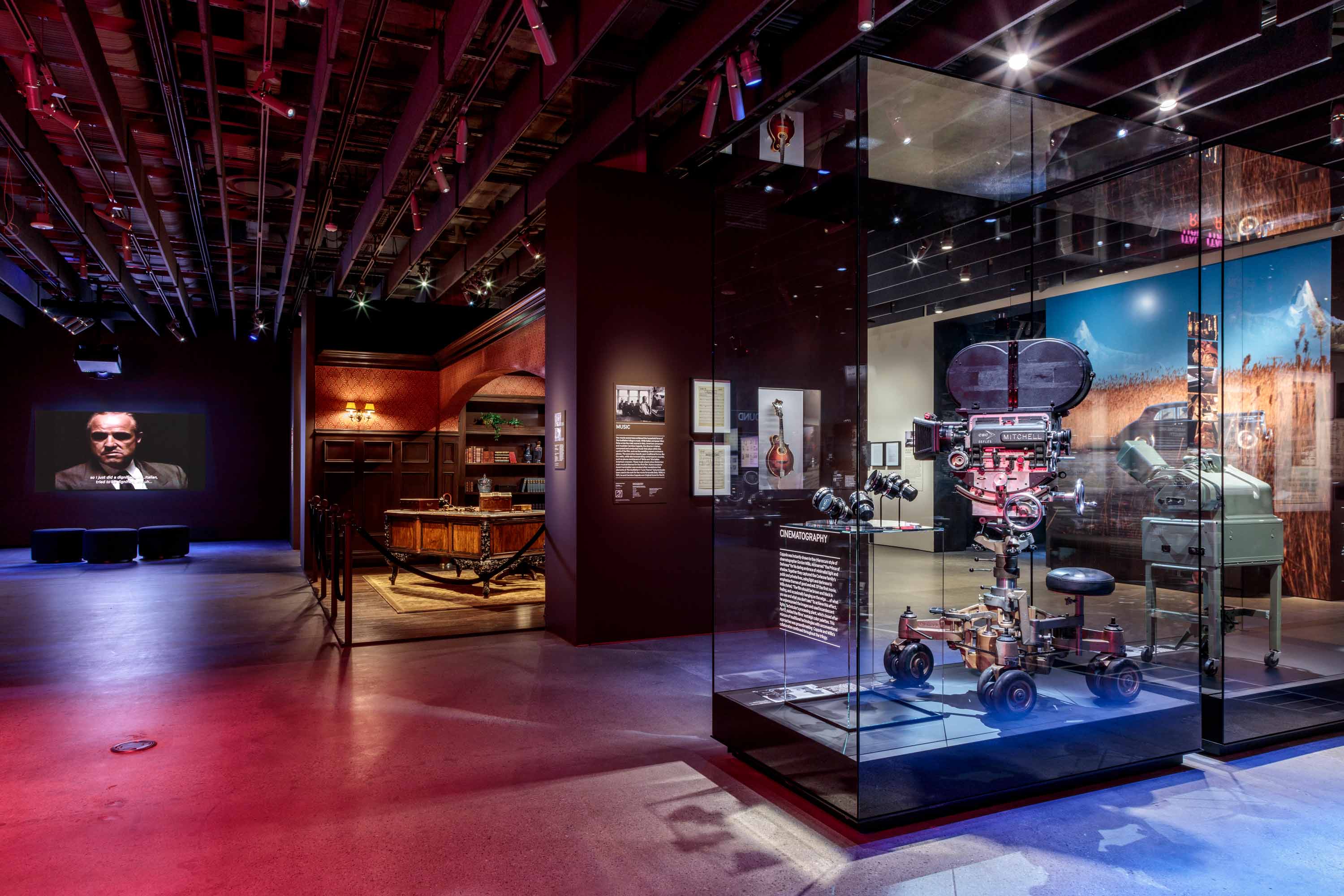 The Art of Moviemaking: The Godfather exhibition at Academy Museum. Glass display cabinets and large screens.
