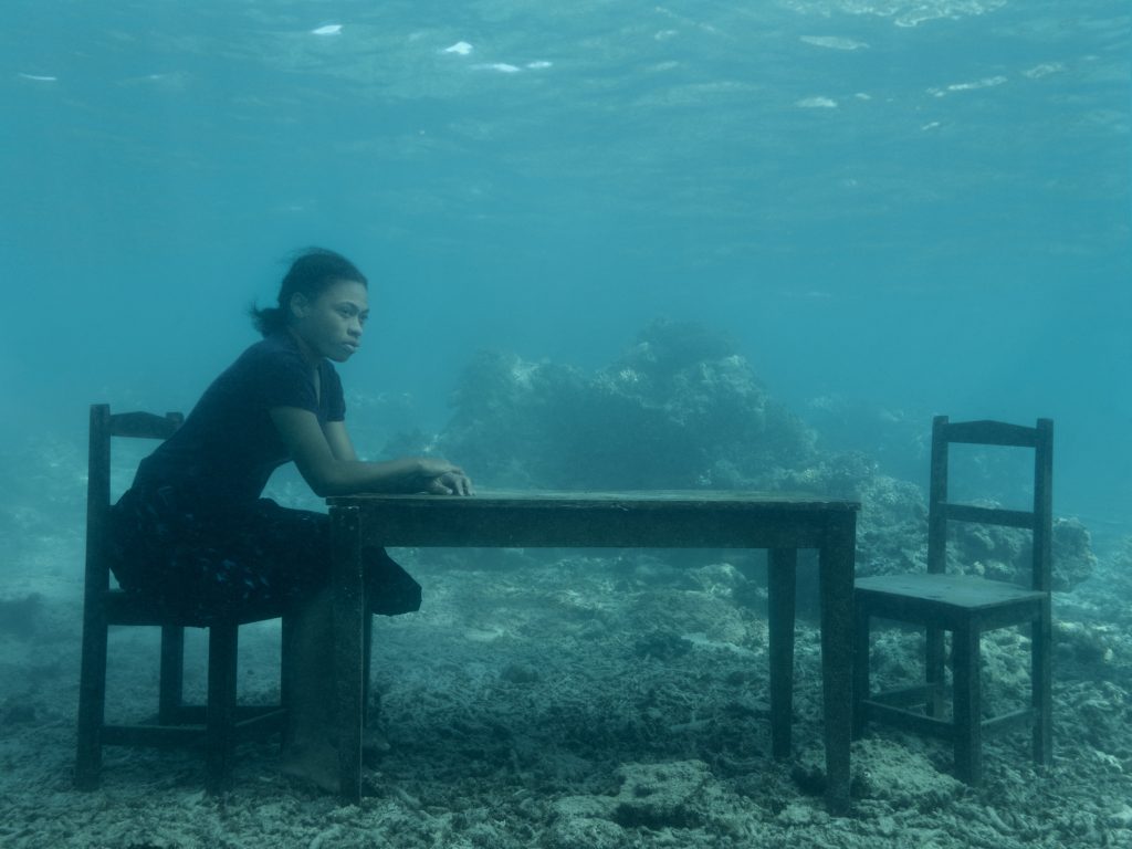 Woman sitting at a table underwater in Fiji