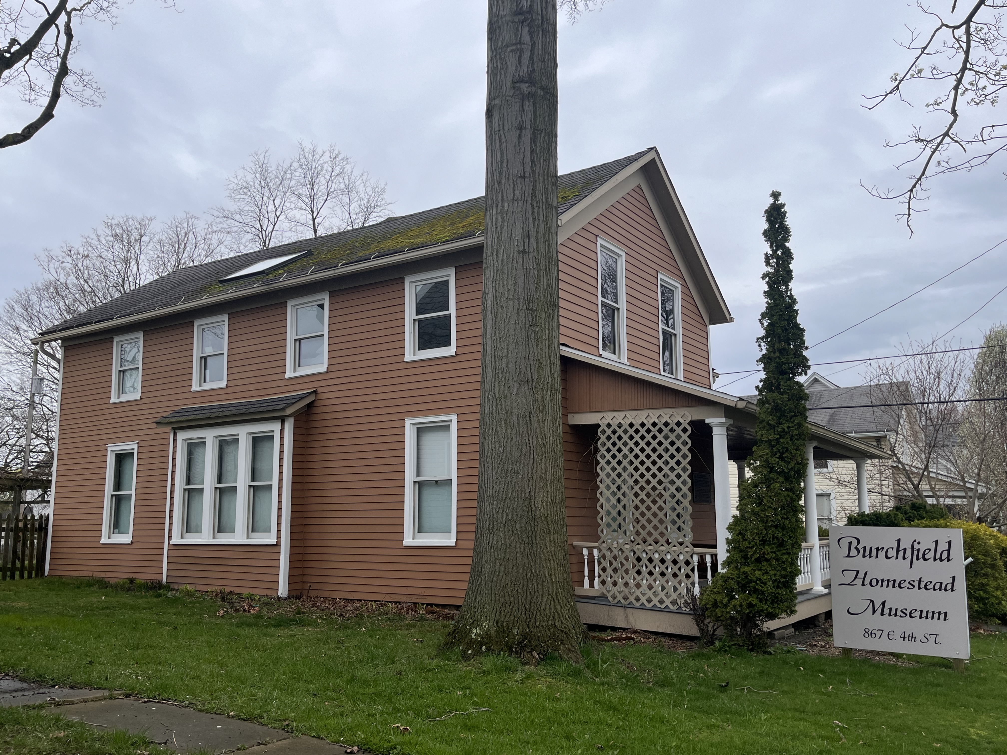 A large oak tree towers over the east side of the Burchfield Homestead.