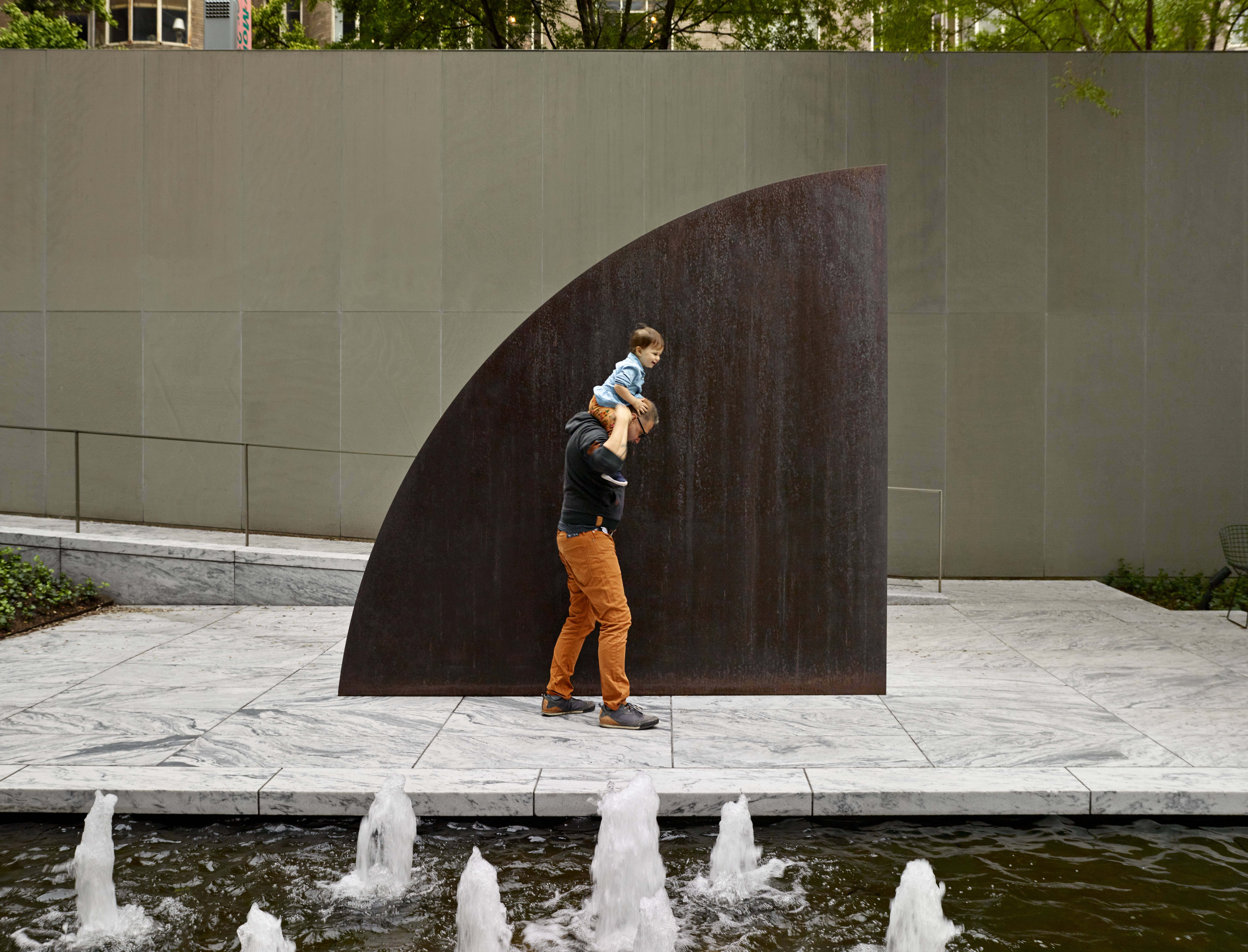 A view of the Abby Aldrich Rockefeller Sculpture Garden with a man carrying a child on his shoulders
