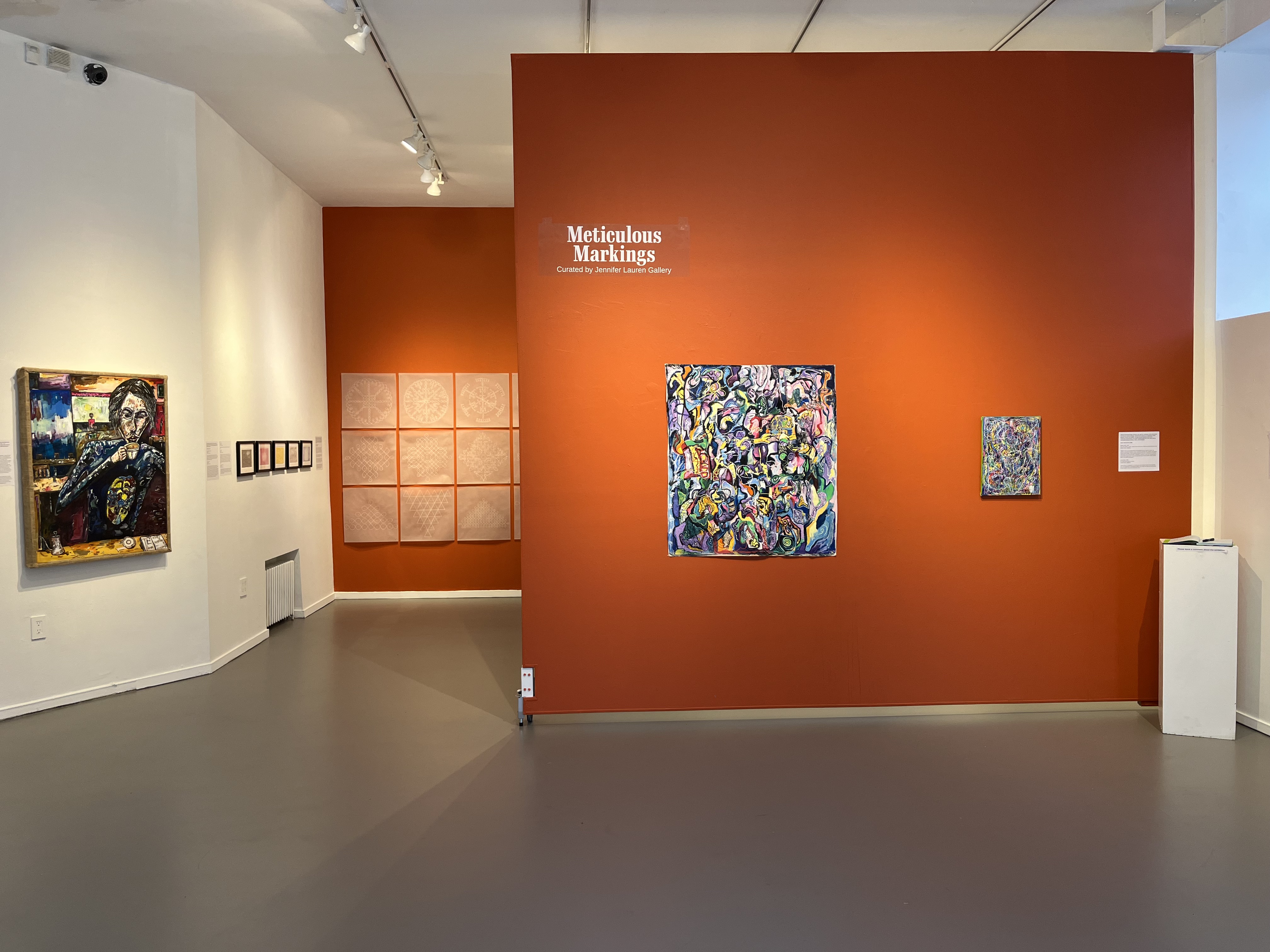 Install shot of "Meticulous Markings" with bright orange accent walls and intricate works on display