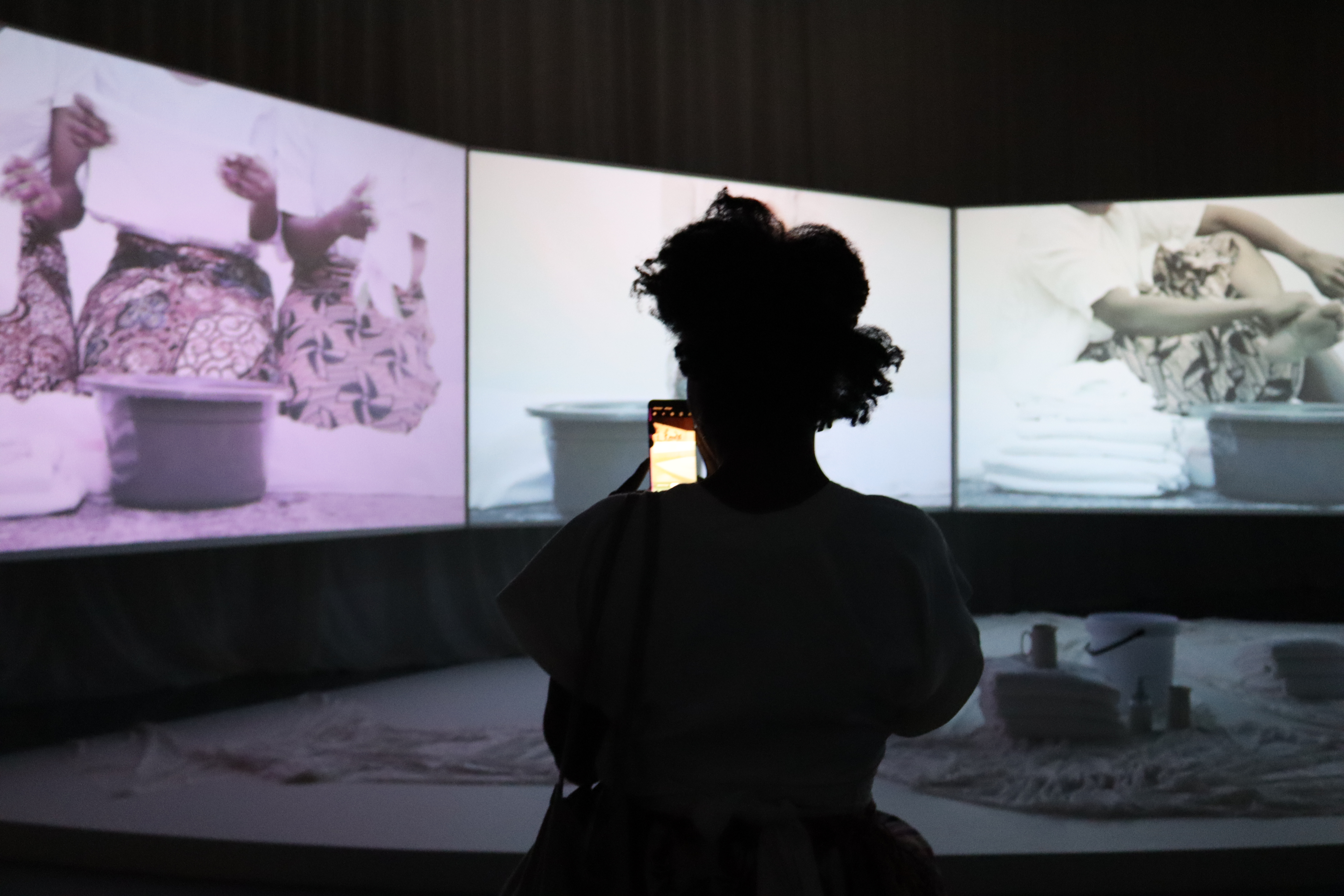 A museum guest in a gallery space photographing an installation work