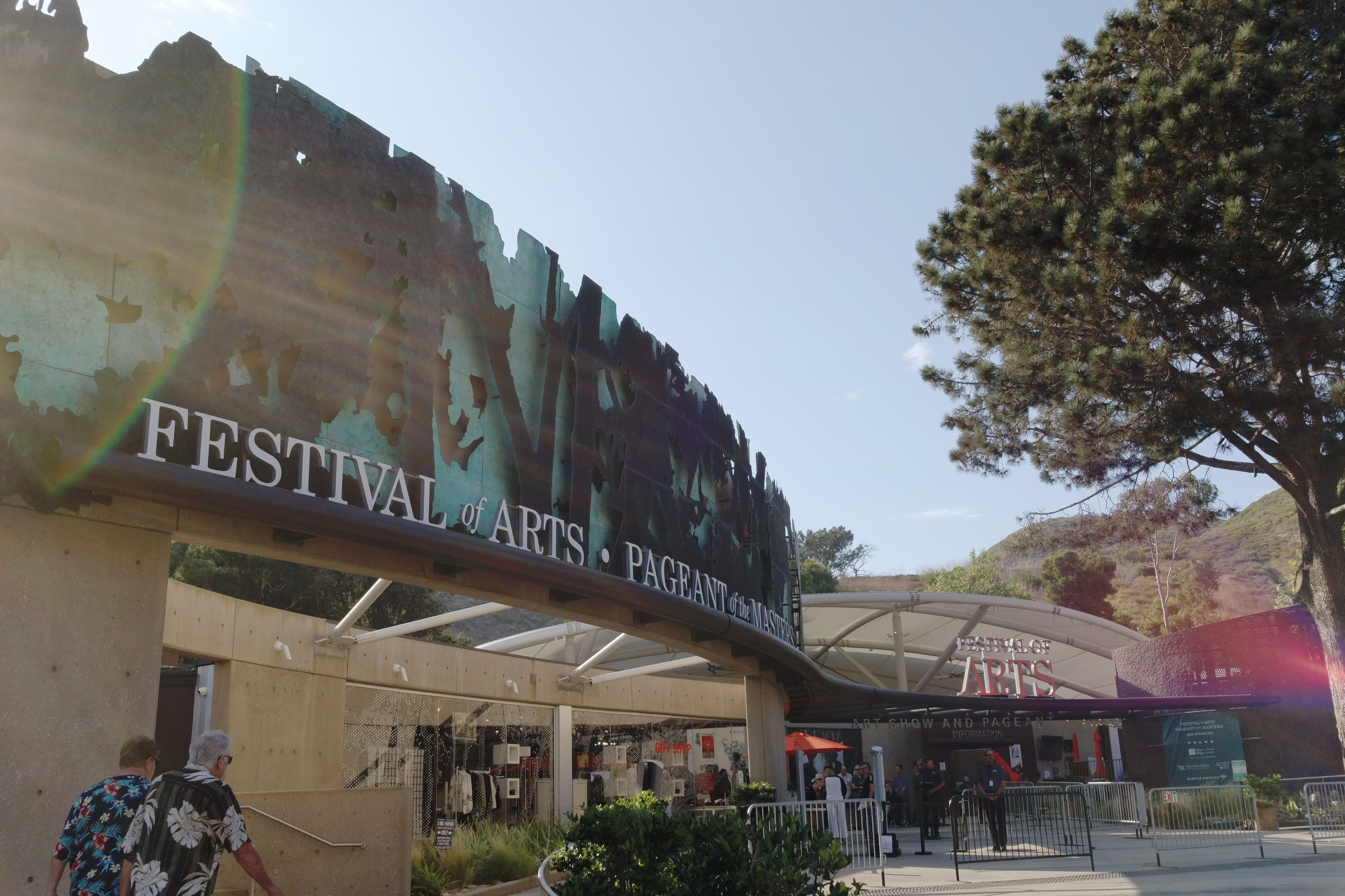A concrete entrance with a large Facade that states "Festival of Arts - Pageant of the Masters" against a silhouette of trees.
