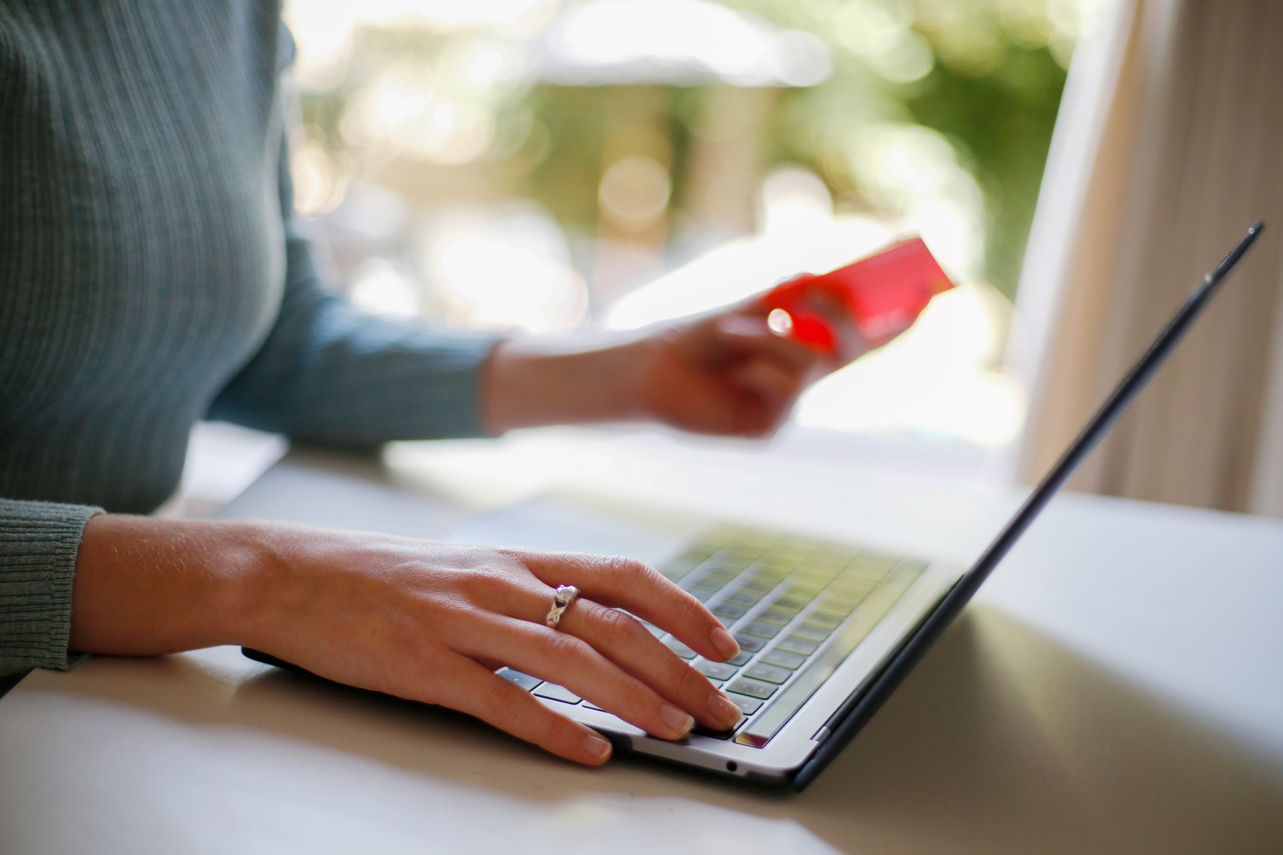 A woman working from home with a laptop computer and bank debit card