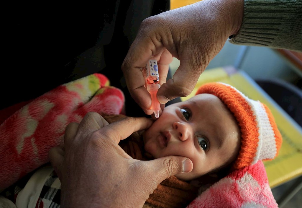 A health worker administers polio vaccine to children during a three-day countrywide vaccination campaign in Peshawar, Pakistan.