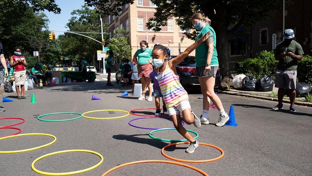 A young girl plays outside in the Jackson Heights neighborhood in Queens, New York during Fresh Air Fund Summer Space, an outdoor summer program for youth supported by Bloomberg Philanthropies, Ford Foundation, and the JPB Foundation.