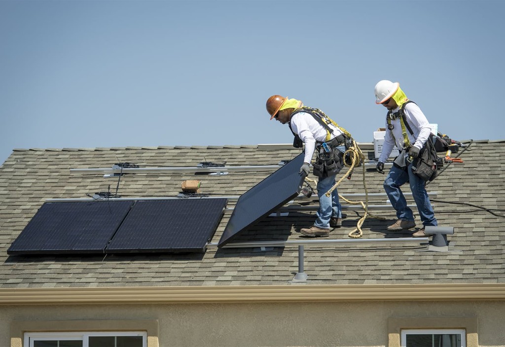 Contractors install SunRun Inc. solar panels on the roof of a new home at the Westline Homes Willowood Cottages community in Sacramento, California. Photo credit: David Paul Morris and Bloomberg