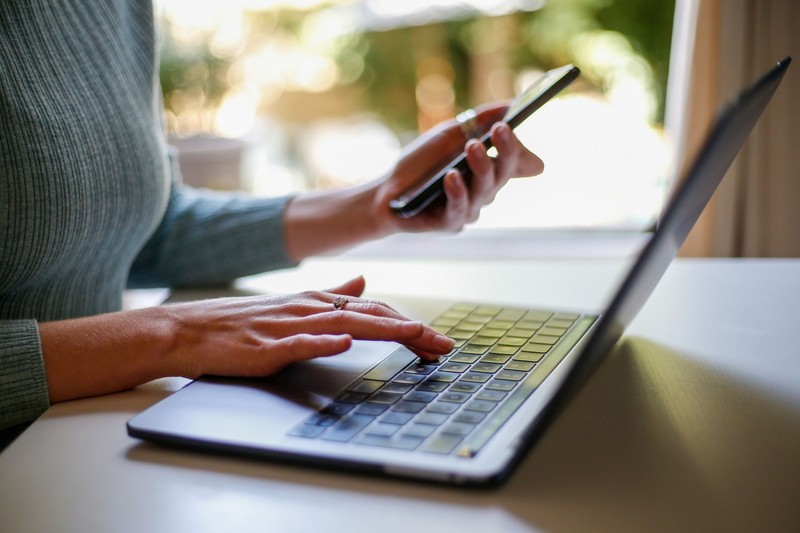 A woman working from home with a laptop computer and mobile phone
