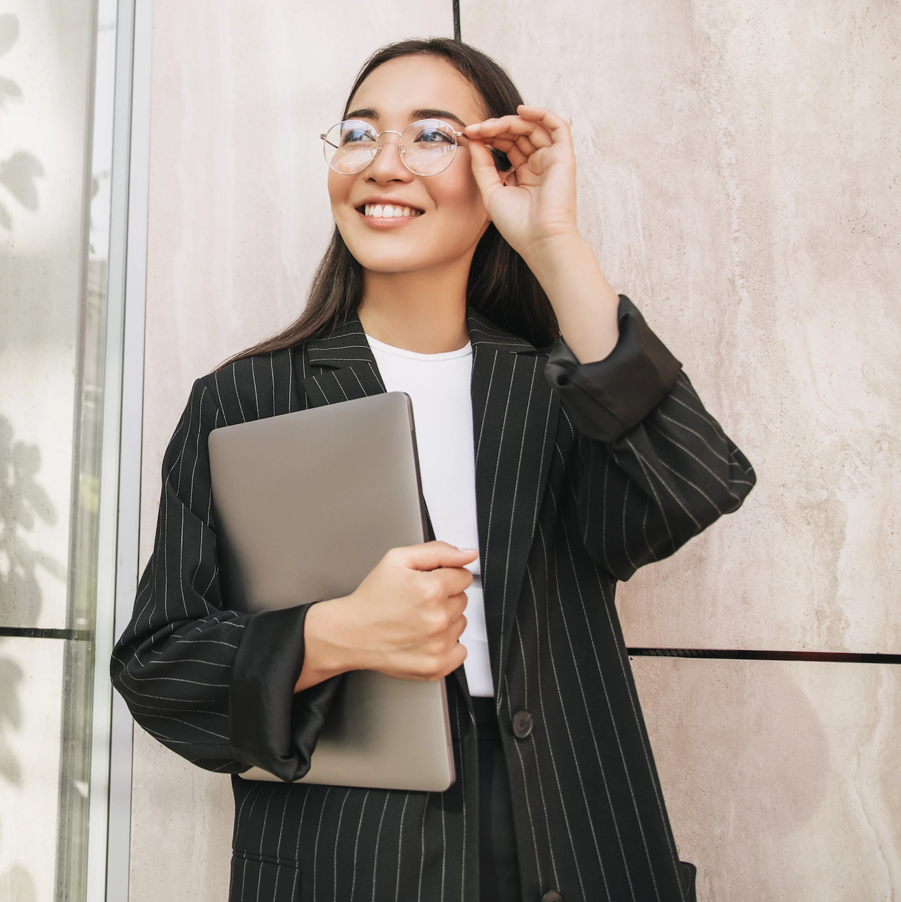 Law sutdent holding her glasses and carrying a laptop