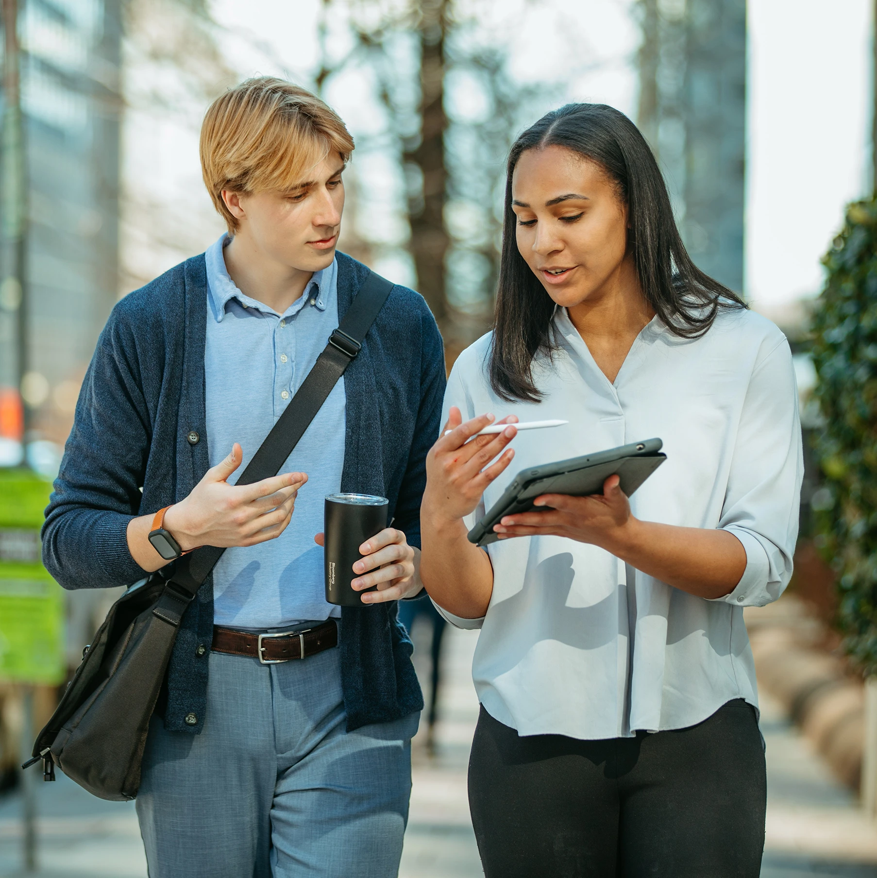 woman explaining something on her tablet to man holding a mug