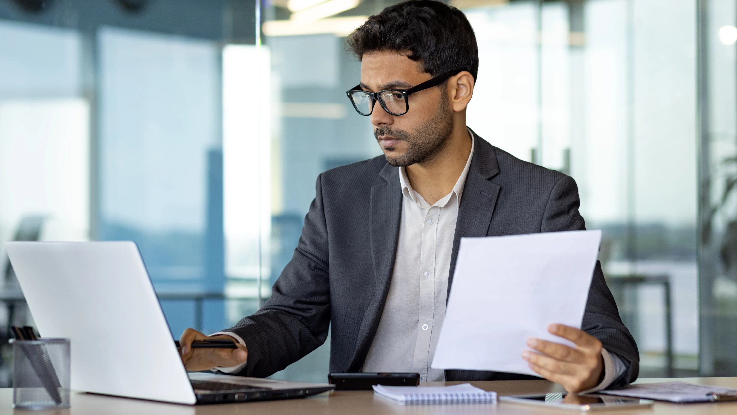 man holding papers and looking at a computer screen