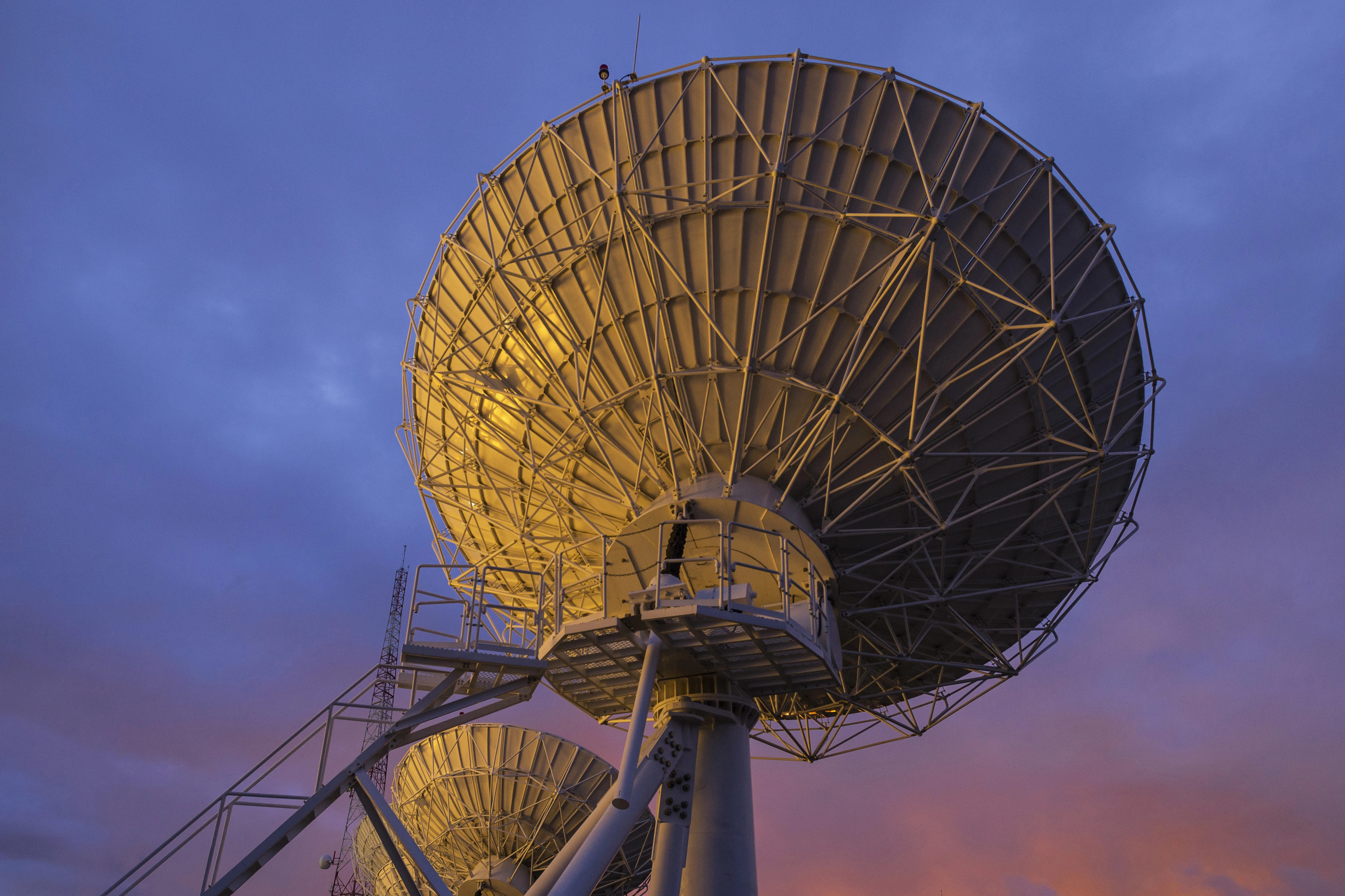 Satellite antennas stand at sunset