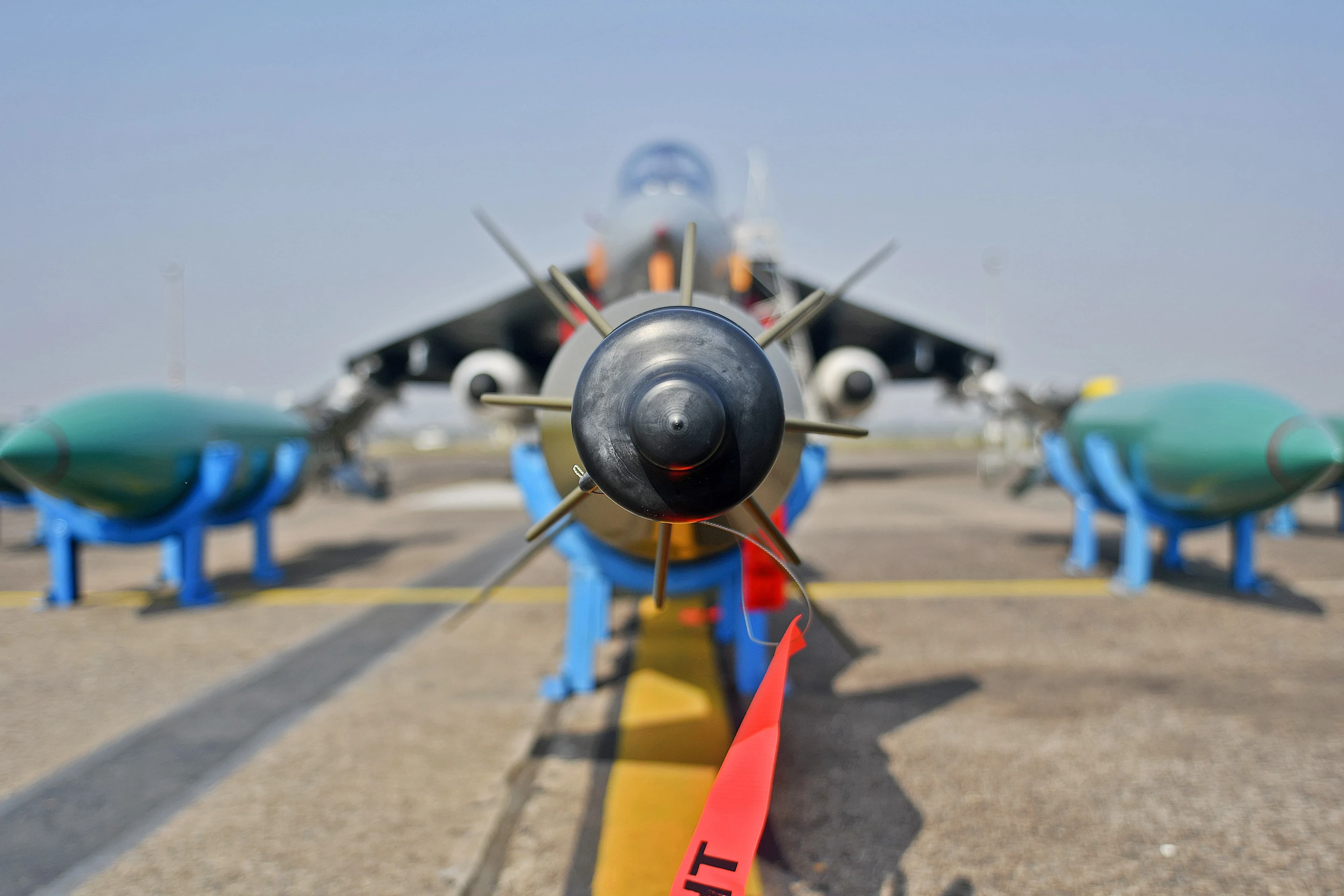 Missiles sit on the tarmac in front of a fighter jet in India.