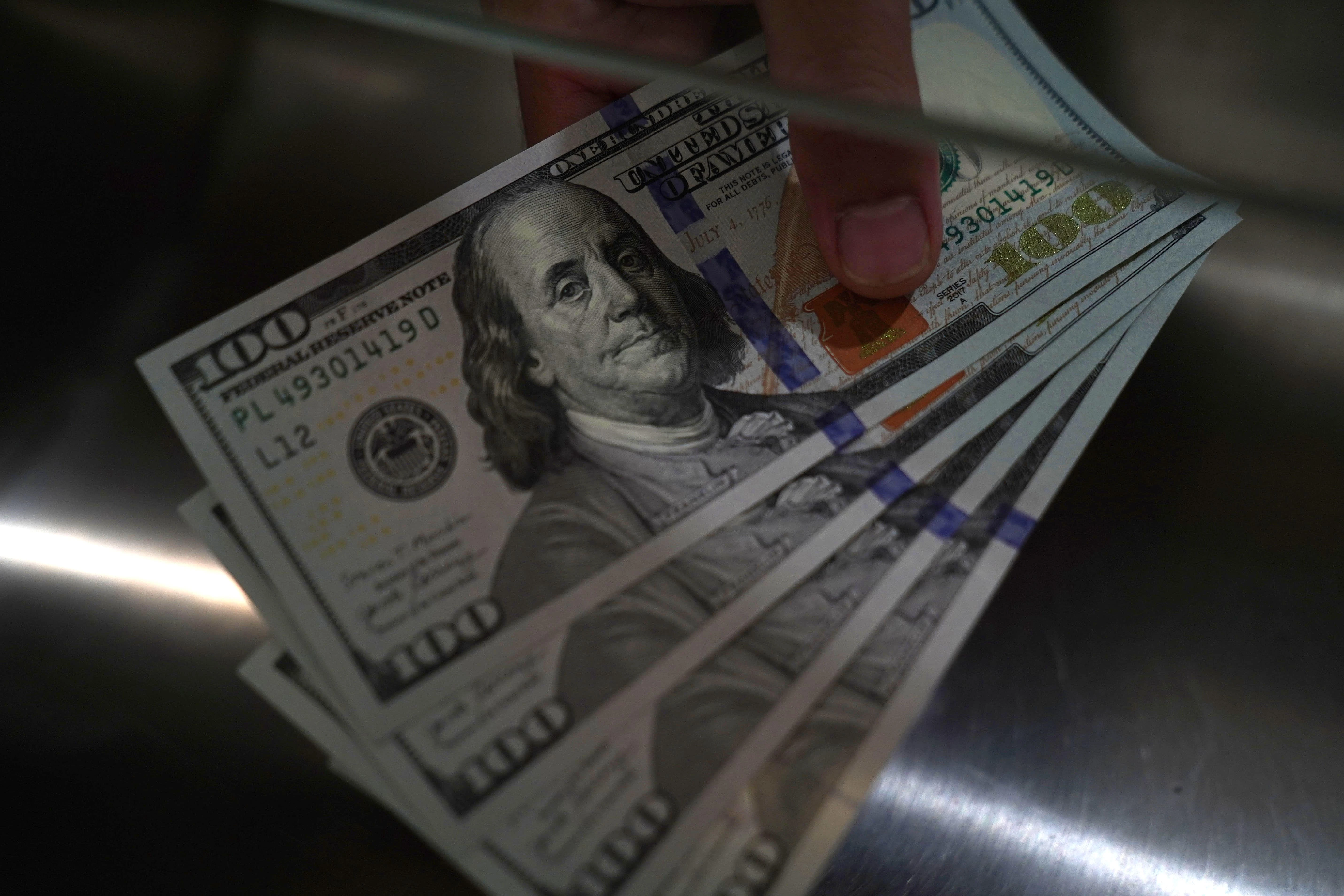 A person holding US 100 dollar banknotes