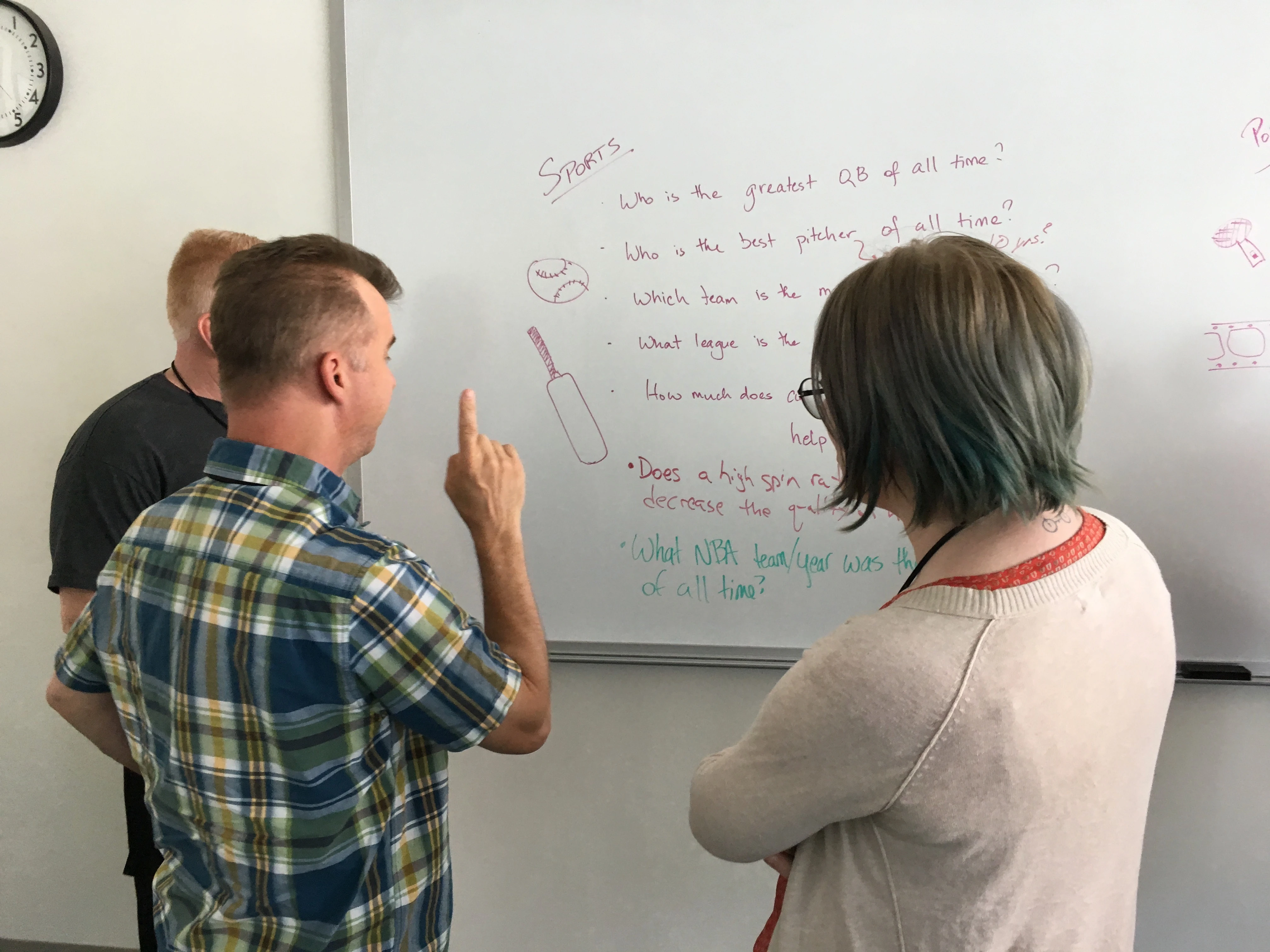 A mentor and two students analyze important data science key takeaways at a classroom whiteboard.