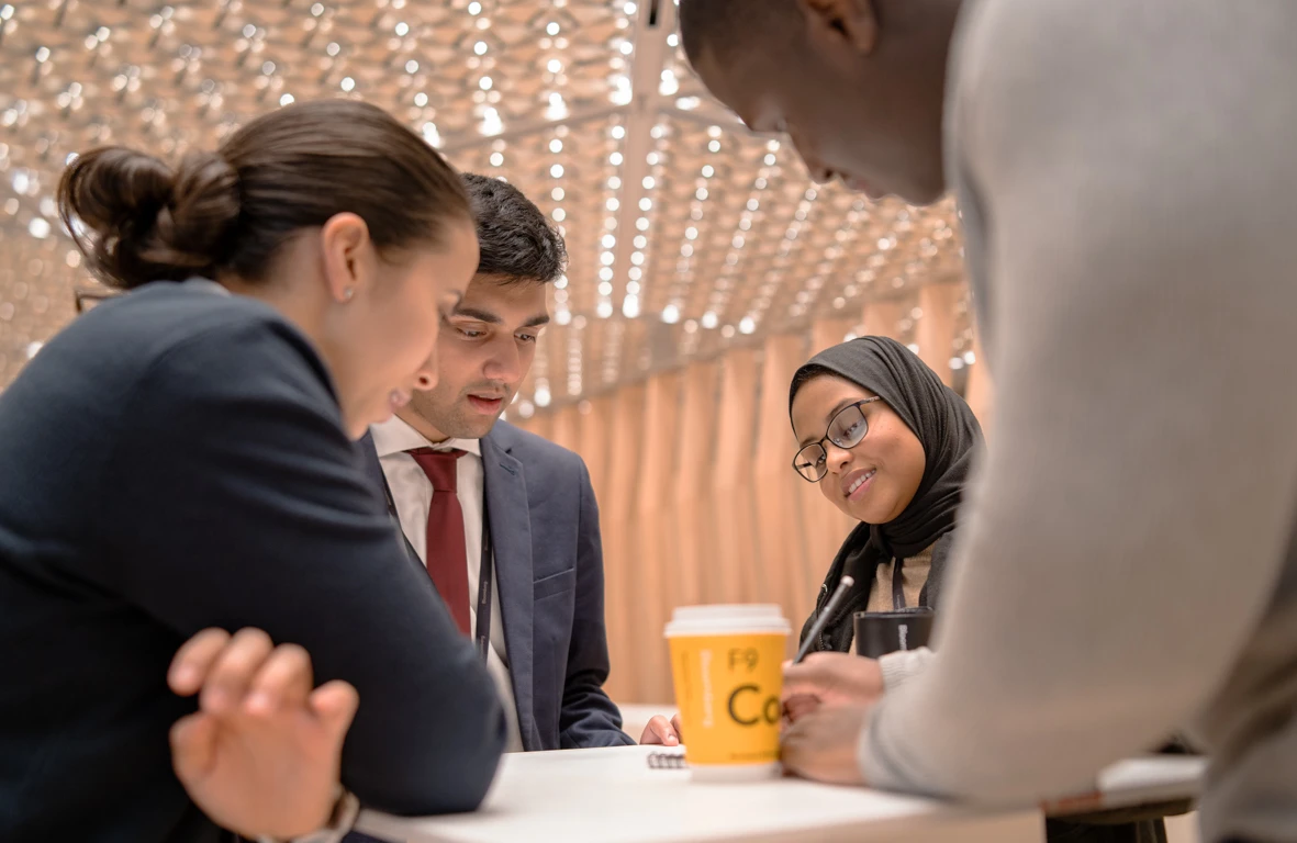 A diverse group of employees discuss a project at the New York offices.