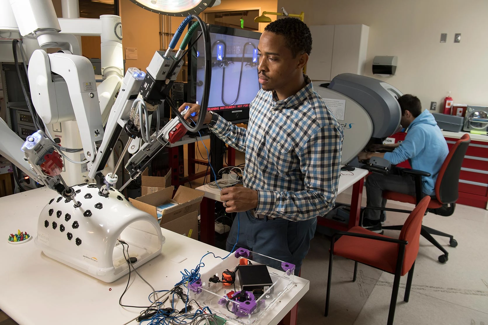 Diverse medical students work with a surgical robot designed for training in laparoscopic surgery.