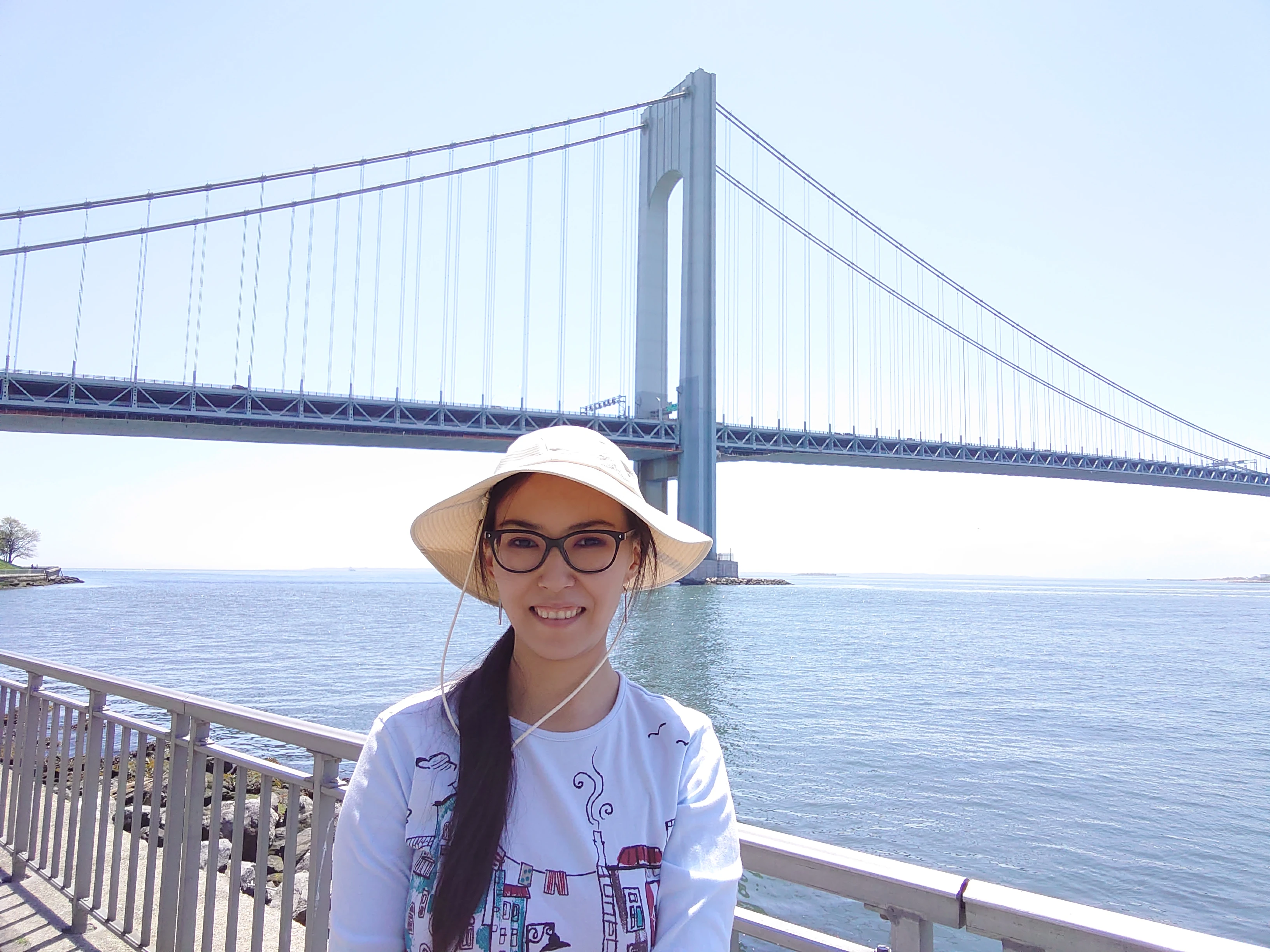 Elmira-Drozdovych Elmira Drozdovych standing outside near a body of water with a bridge in the background.