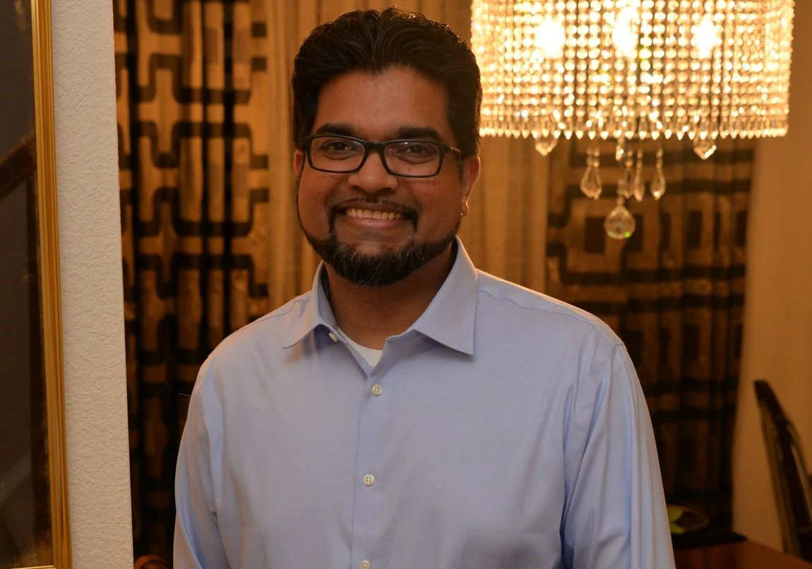 Khawar-Farooqi Khawar Farooqi standing in in front of an overhead chandelier