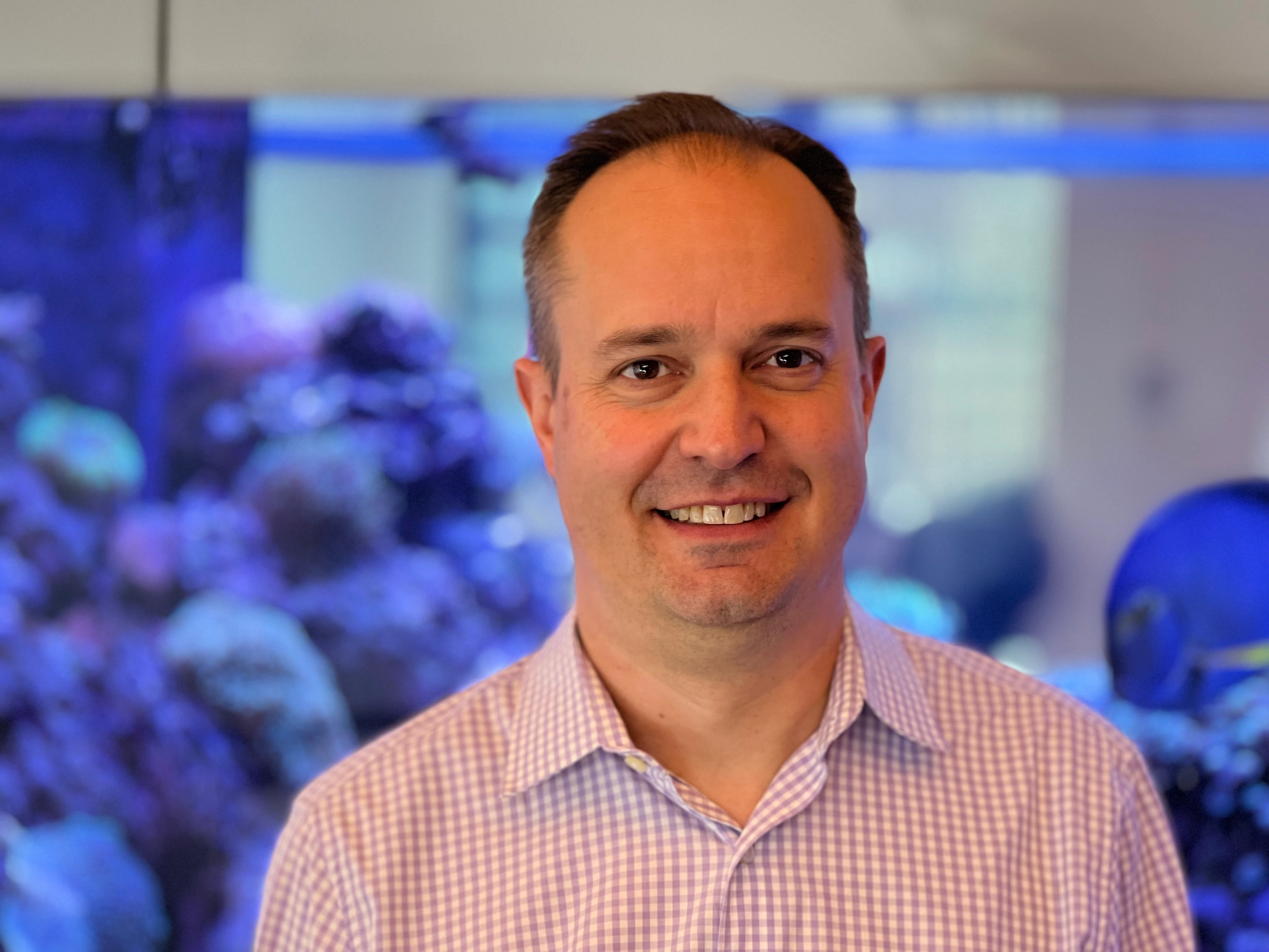 Matthew-R-Newton-select Matthew R Newton standing in front of a fish tank in the Bloomberg office in NYC