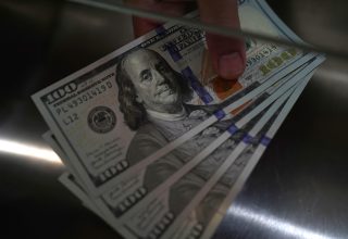 A person holding US 100 dollar banknotes